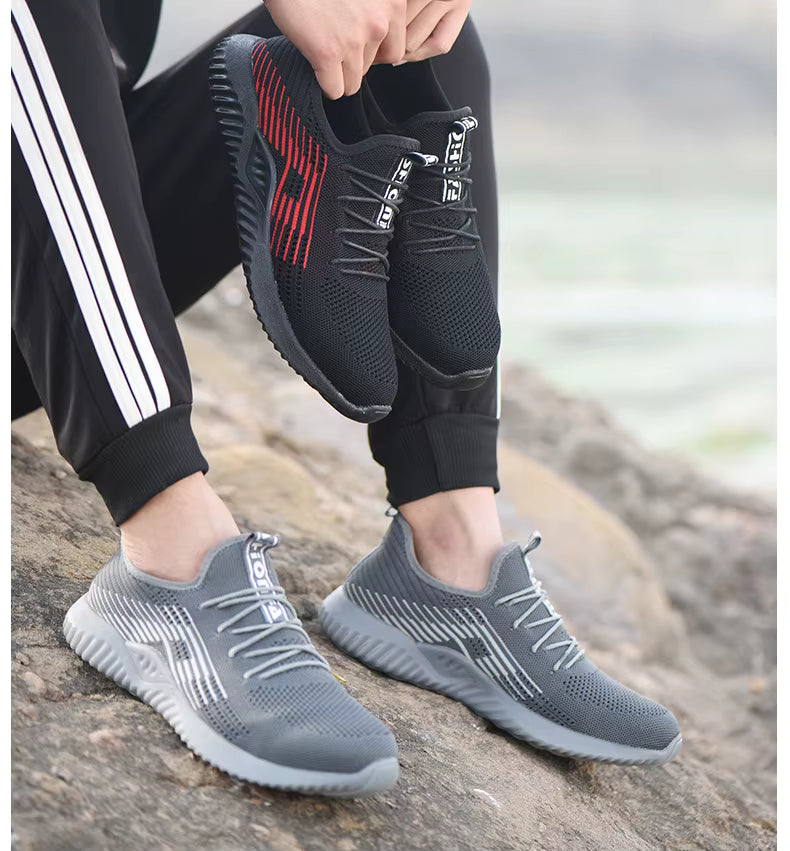 Black and grey steel toe cap safety shoes held and worn outdoors — lifestyle comparison of both colour options
